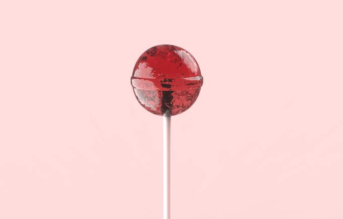 A purple lollipop on a pink background