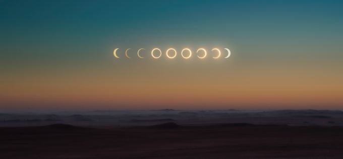 Desert landscape with multiple exposures of the phases of a solar eclipse in the sky