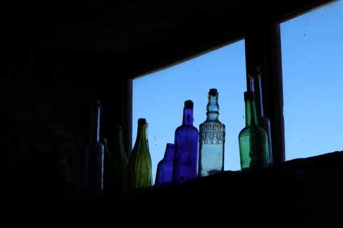 Several bottles on a windowsill. 