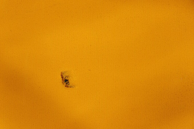 A hole punctures a piece of orange fabric
