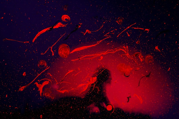 Abstract red and black splatter. Within is a silhouette of a person.