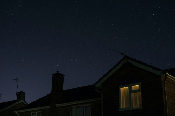 Single illuminated house window under a night sky